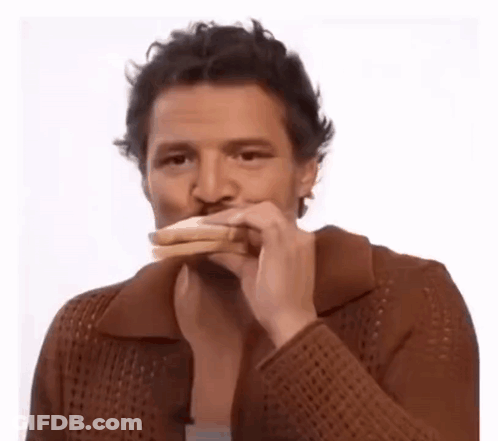 A Man In A Brown Sweater Is Eating A Sandwich With His Mouth Open . GIF