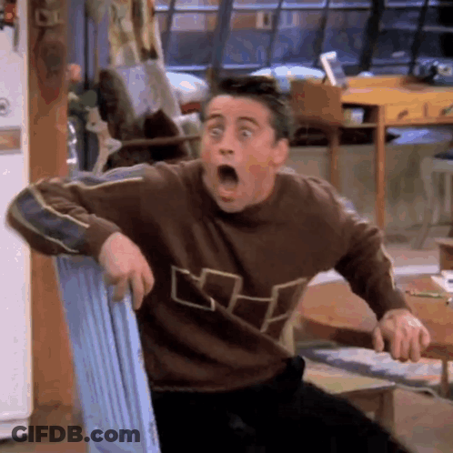 A Man In A Brown Sweater Is Sitting In A Chair With His Mouth Open . GIF