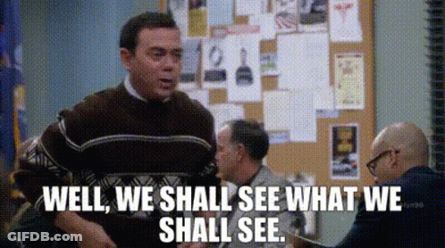 A Man In A Brown Sweater Is Standing In Front Of A Bulletin Board And Says Well We Shall See What We Shall See GIF