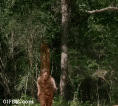 A Man In A Brown Vest And Pants Is Walking Through A Forest GIF