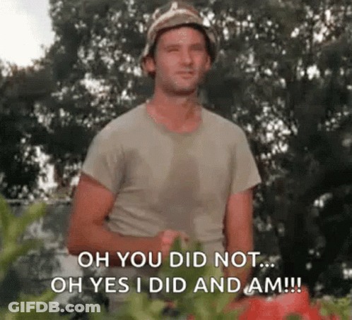 A Man In A Bucket Hat Is Standing In Front Of A Bunch Of Tomatoes And Tomatoes . GIF