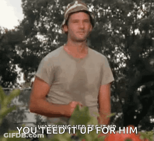 A Man In A Bucket Hat Is Standing In Front Of A Tomato Plant And Says `` You Feed It Up For Him '' . GIF