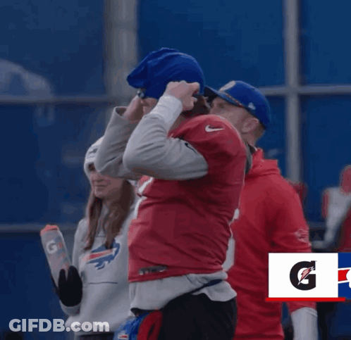 A Man In A Buffalo Bills Jersey Stands Next To Another Man GIF