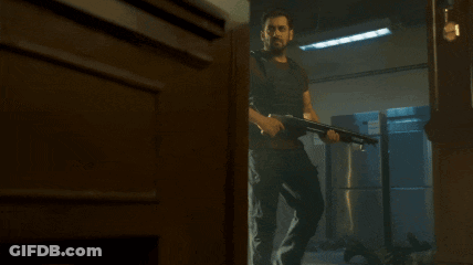 A Man In A Bullet Proof Vest Is Holding A Gun GIF