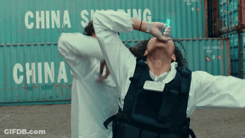 A Man In A Bullet Proof Vest Is Standing In Front Of A China Shipping Container GIF