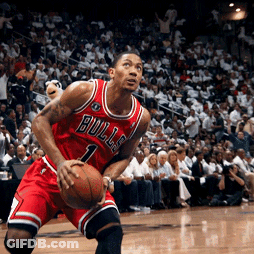 A Man In A Bulls Jersey Is Holding A Basketball In Front Of A Crowd GIF