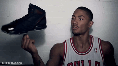 A Man In A Bulls Jersey Is Holding A Black Shoe GIF