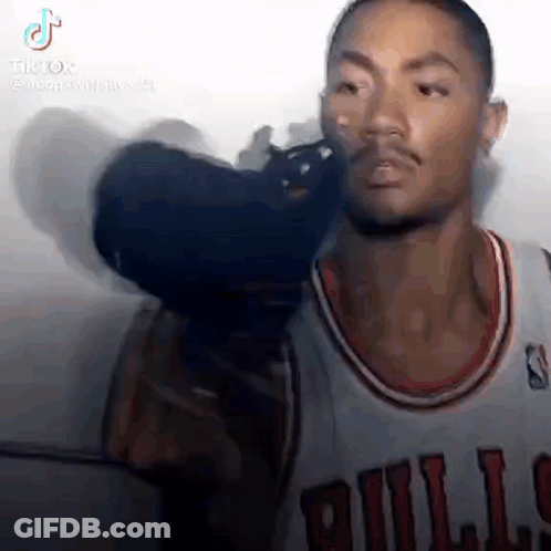 A Man In A Bulls Jersey Is Holding A Camera Over His Head . GIF