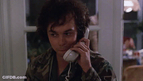 A Man In A Camo Shirt Is Talking On A Telephone GIF