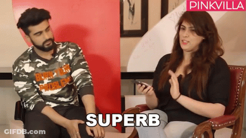 A Man In A Camo Shirt Sits Next To A Woman In A Black Shirt With The Word Superb On It GIF