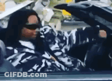 A Man In A Camouflage Jacket Is Driving A Car . GIF