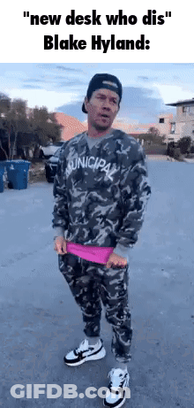 A Man In A Camouflage Shirt And Pants Is Standing On A Street . GIF