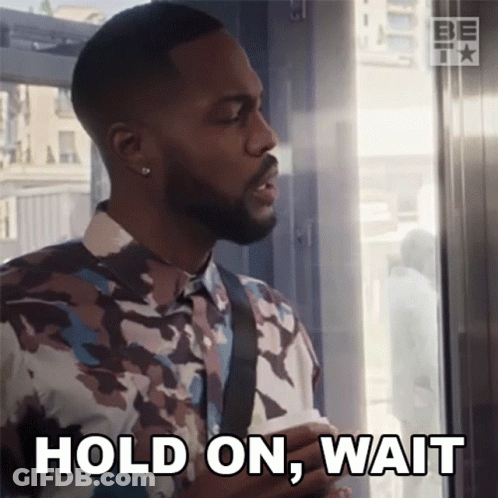 A Man In A Camouflage Shirt Is Holding A Piece Of Paper And Says Hold On Wait GIF