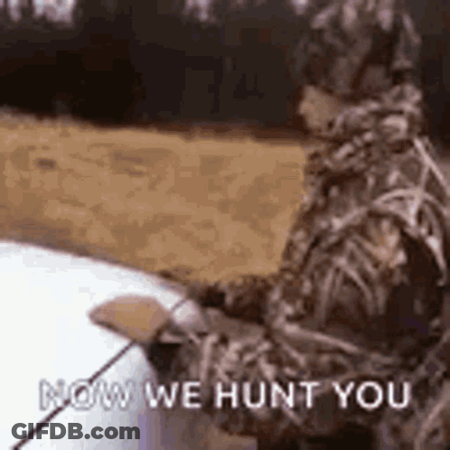 A Man In A Camouflage Suit Is Standing Next To A Car Holding A Fishing Rod And A Fishing Pole . GIF