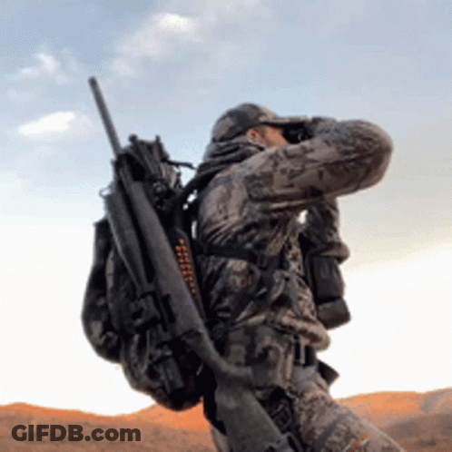 A Man In A Camouflage Uniform Is Holding A Rifle And Binoculars GIF