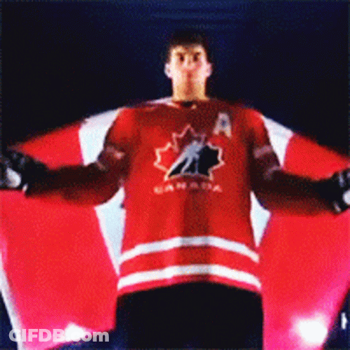 A Man In A Canada Jersey Is Holding A Large Canadian Flag GIF