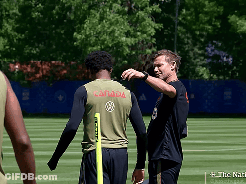 A Man In A Canada Jersey Talks To Another Man On A Field GIF