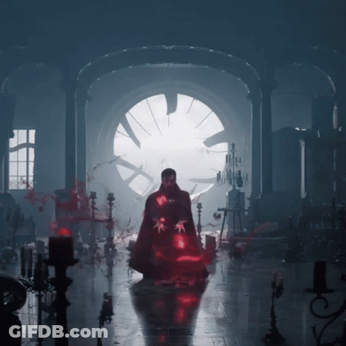 A Man In A Cape Is Standing In A Dark Room With Candles GIF
