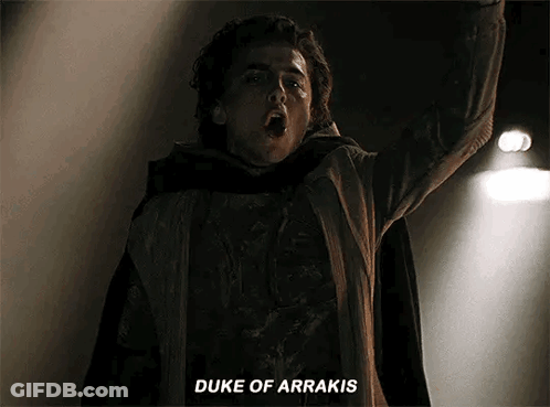 A Man In A Cape Is Standing In The Dark With His Arms In The Air And Says `` Duke Of Arrakis '' . GIF