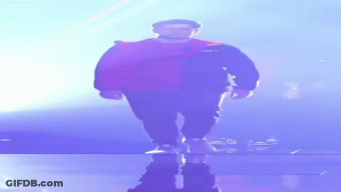 A Man In A Cape Is Walking On A Stage In The Dark GIF