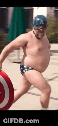 A Man In A Captain America Costume Is Holding A Shield And Wearing A Mask . GIF