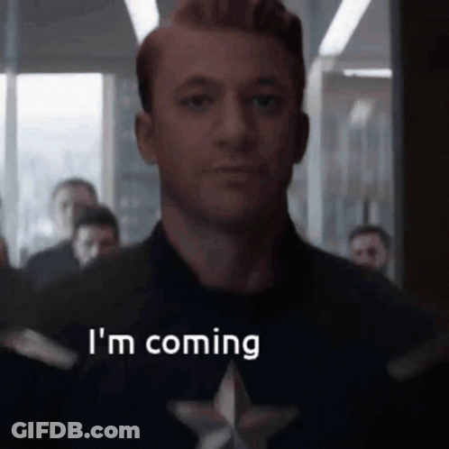 A Man In A Captain America Costume Is Saying `` I 'M Coming '' In Front Of A Crowd Of People . GIF