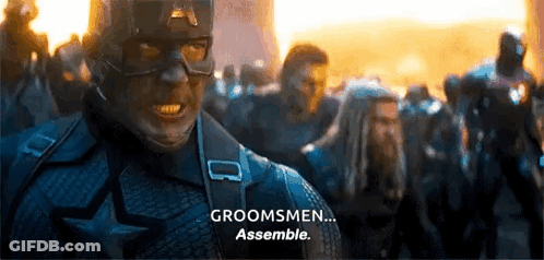 A Man In A Captain America Costume Is Standing In Front Of A Crowd Of People . GIF