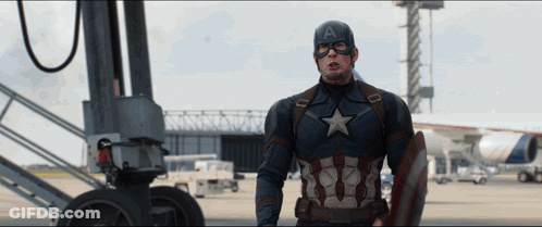 A Man In A Captain America Costume Is Standing In Front Of An Airplane GIF