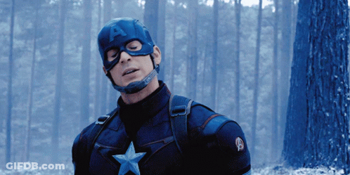 A Man In A Captain America Costume Is Standing In The Woods GIF
