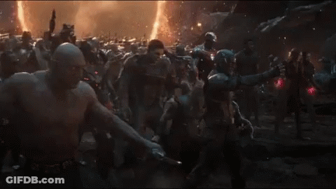 A Man In A Captain America Costume Stands In Front Of A Crowd Of People GIF