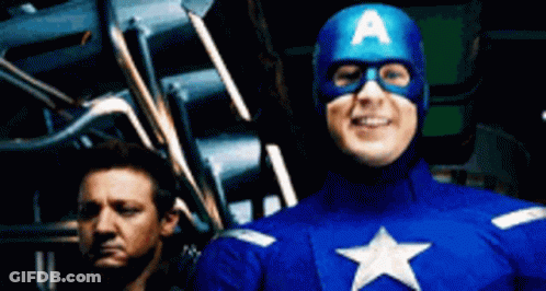 A Man In A Captain America Costume Stands Next To Another Man GIF