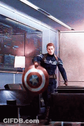 A Man In A Captain America Uniform Is Holding A Shield In A Living Room . GIF