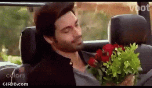 A Man In A Car Holding A Bouquet Of Red Roses GIF