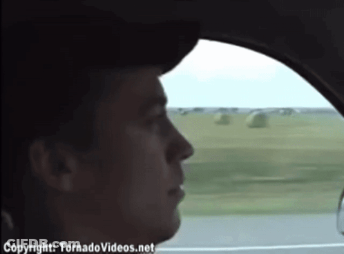 A Man In A Car Is Looking Out The Window And The Website Tornadovideos.net Is Visible GIF