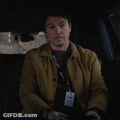 A Man In A Car With A Lanyard Around His Neck That Says ' Kevin A. Scott ' GIF