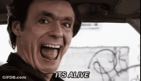 A Man In A Car With His Mouth Open And The Words " It 'S Alive " On The Bottom Right GIF