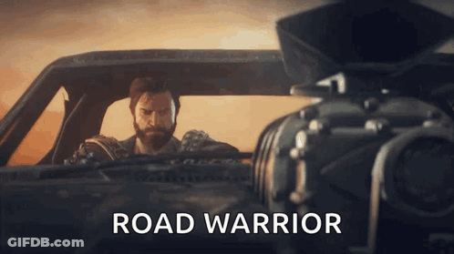 A Man In A Car With The Word Road Warrior On The Bottom Right GIF