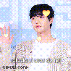 A Man In A Cardigan Is Waving His Hand In Front Of A Sign That Says Saluda Si Eres De Fist GIF