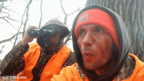 A Man In A Carhartt Hat Looks Through Binoculars GIF