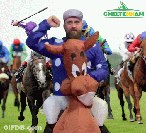 A Man In A Cartoon Horse Costume Rides A Horse In A Race GIF