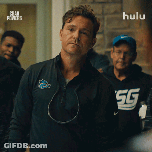 A Man In A Chad Powers Shirt Stands In Front Of A Hulu Logo GIF