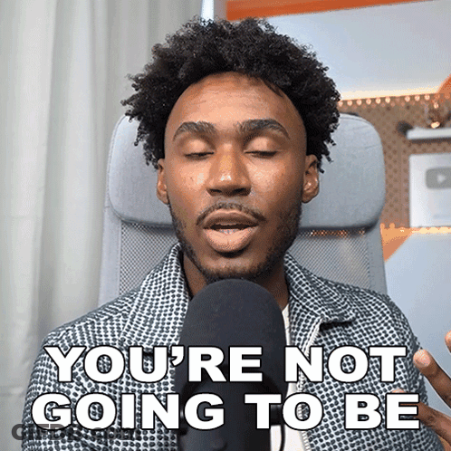 A Man In A Chair Says " You 'Re Not Going To Be " In Front Of A Microphone GIF