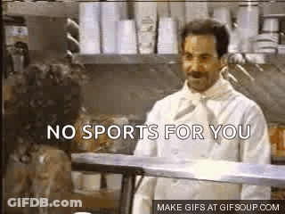 A Man In A Chef 'S Coat Is Standing In A Kitchen Talking To A Woman . GIF