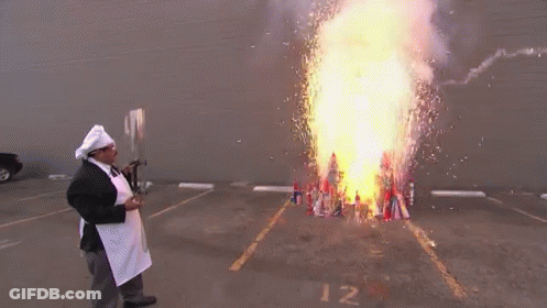 A Man In A Chef 'S Hat And Apron Stands In Front Of A Large Fire GIF