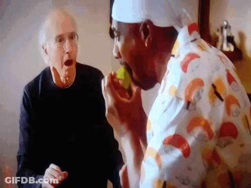 A Man In A Chef 'S Hat Is Eating A Lemon While Another Man Watches GIF