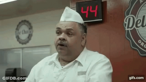 A Man In A Chef 'S Hat Stands In Front Of A Digital Clock That Says 44 GIF