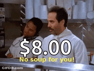 A Man In A Chef 'S Uniform Is Standing In A Kitchen Talking On A Phone While Another Man Looks On . GIF
