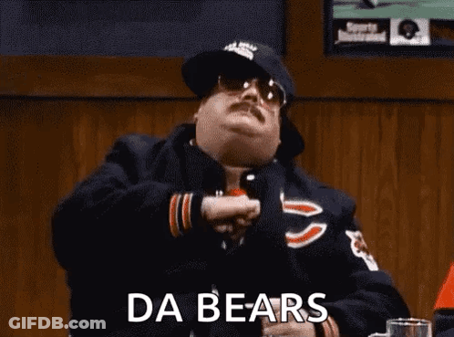 A Man In A Chicago Bears Jacket Is Sitting At A Table In A Bar With His Arms In The Air . GIF
