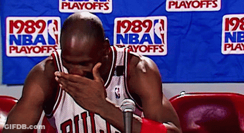 A Man In A Chicago Bulls Jersey Covering His Face In Front Of A Nba Playoffs Banner GIF