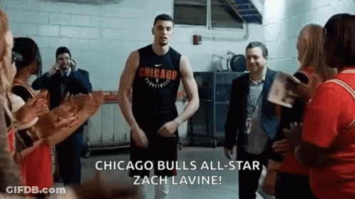 A Man In A Chicago Bulls Jersey Is Standing In A Room With People . GIF